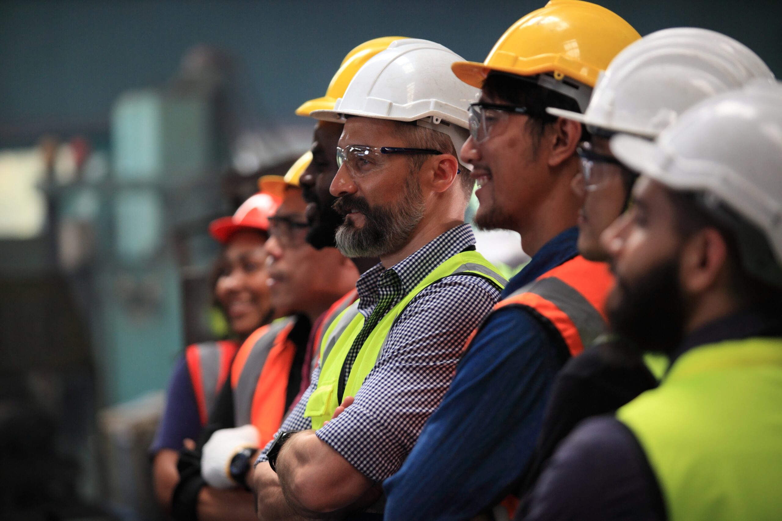 Workers waiting onsite for OSHA, MSHA, or DOT compliance health testing. Industrial workers in safety gear receiving onsite OSHA, MSHA, and DOT-compliant health and safety briefing.